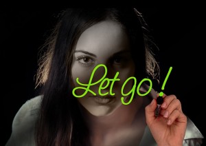 Girl writing "let go" on a window while looking into you